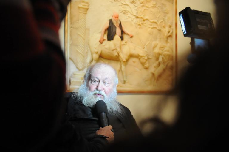 Austrian artist Herman Nitsch poses by an image of himself superimposed on an erotic fresco at the Casoria Contemporary Art Museum (CAM) near Naples on November 28, 2013